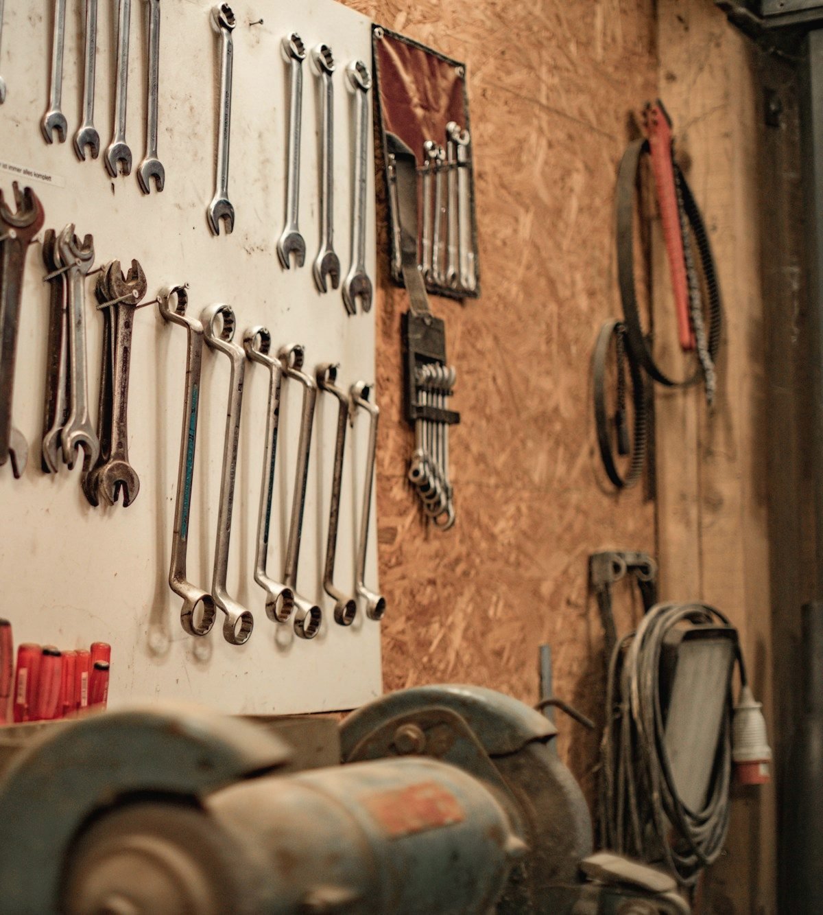 Wrenches hanging on a shop wall above a bench grinder